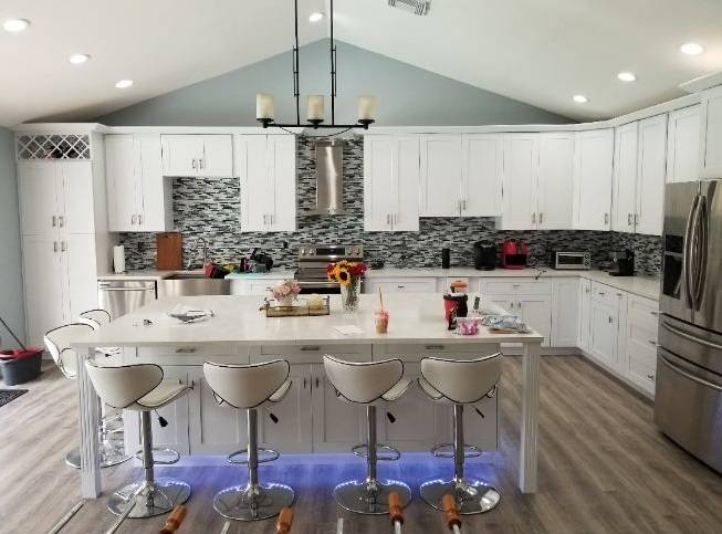 Bright white kitchen remodel with a large island, mosaic tile backsplash, and vaulted ceiling
