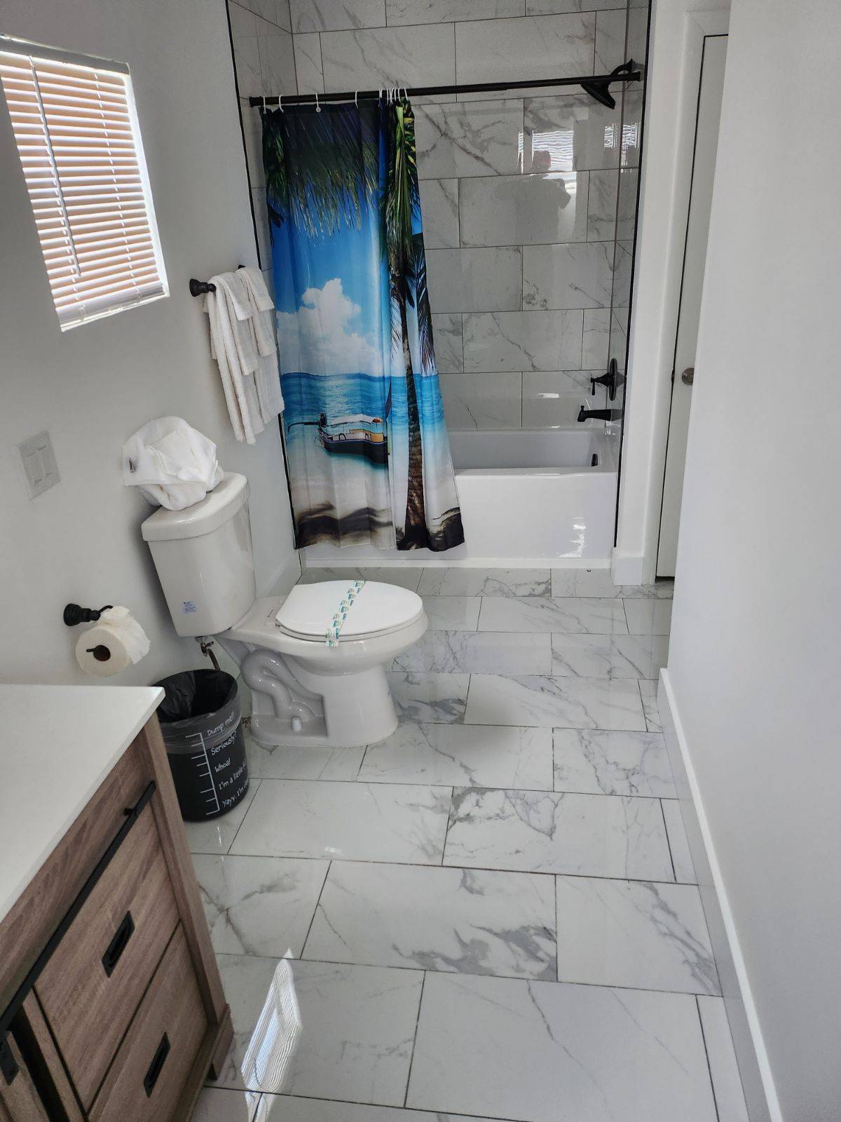 Remodeled bathroom with marble-look tile around the tub and matching marble-look floor tile