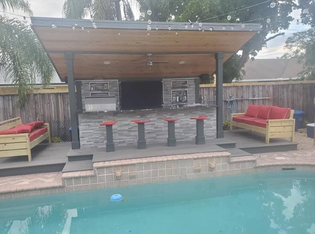 Poolside outdoor bar with a wood-paneled roof, stone-veneer counter, and bar seating