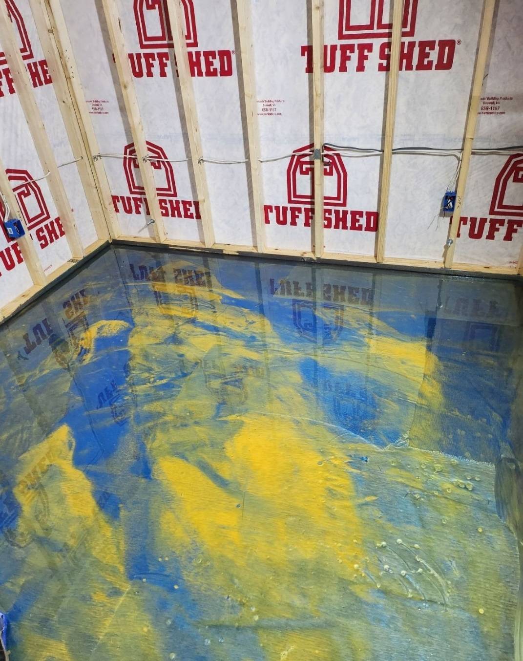 Yellow and blue metallic epoxy floor in a shed with framed stud walls