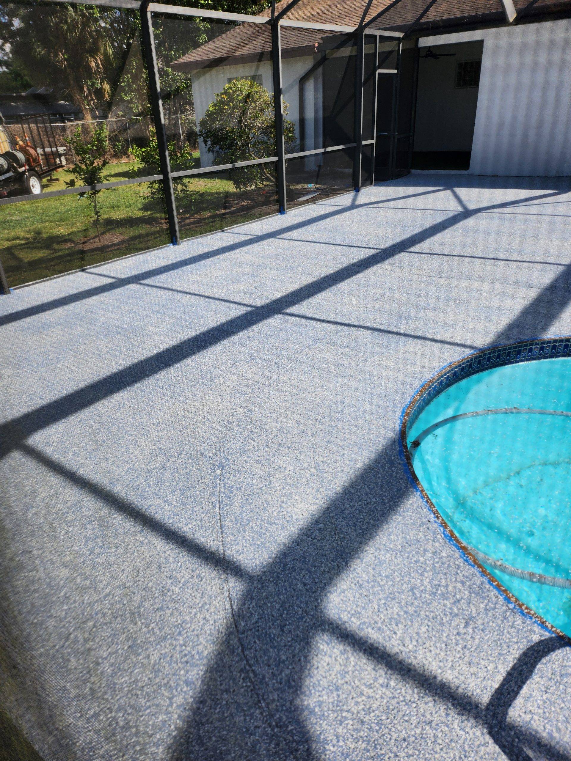 Resurfaced speckled pool deck inside a screened enclosure, seen from the side