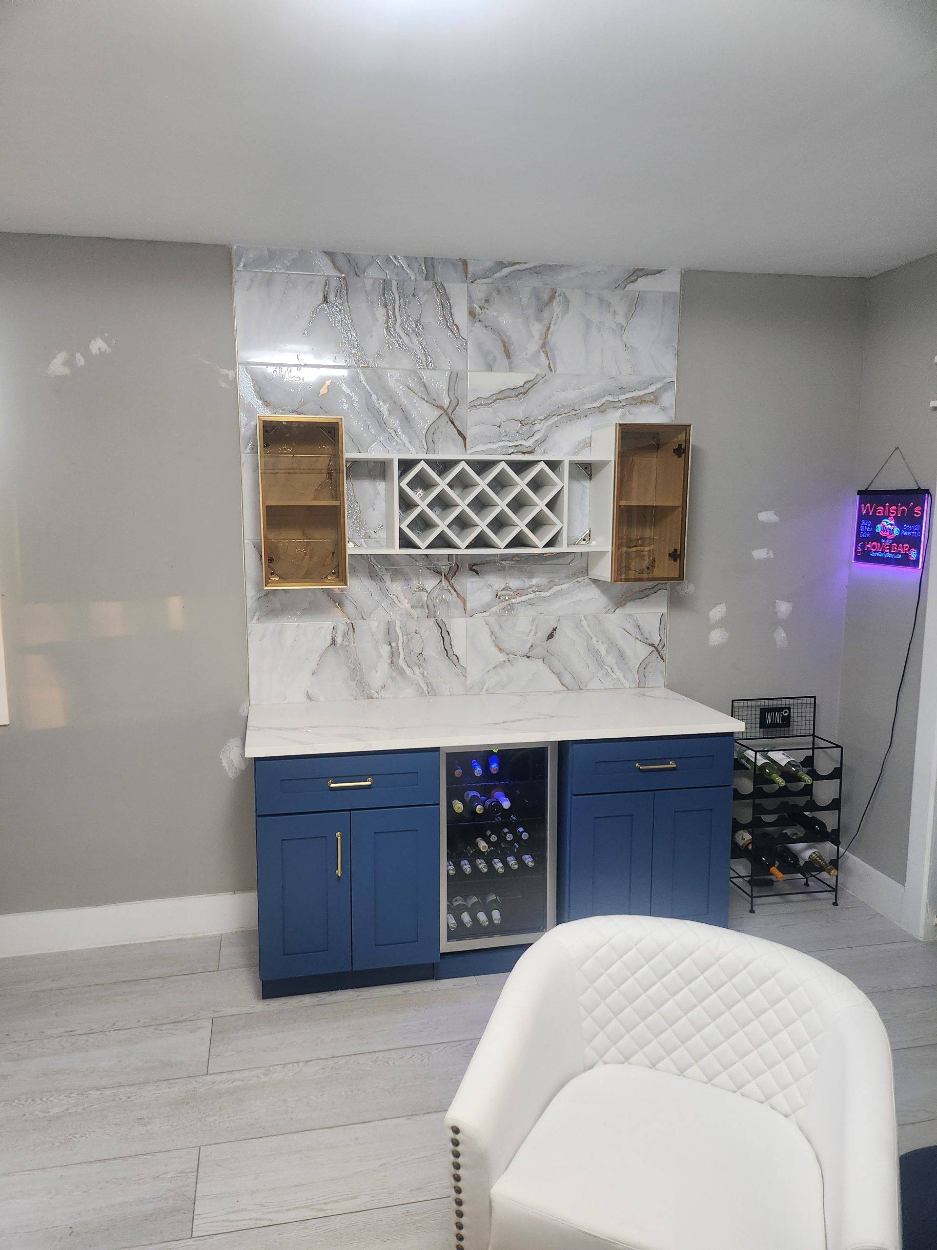 Custom home bar with navy cabinets, a wine rack, glass-front upper cabinets, and a marble-look tile backsplash